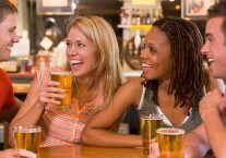 group-of-young-friends-drinking-and-laughing-in-a-bar-SBI-301057554